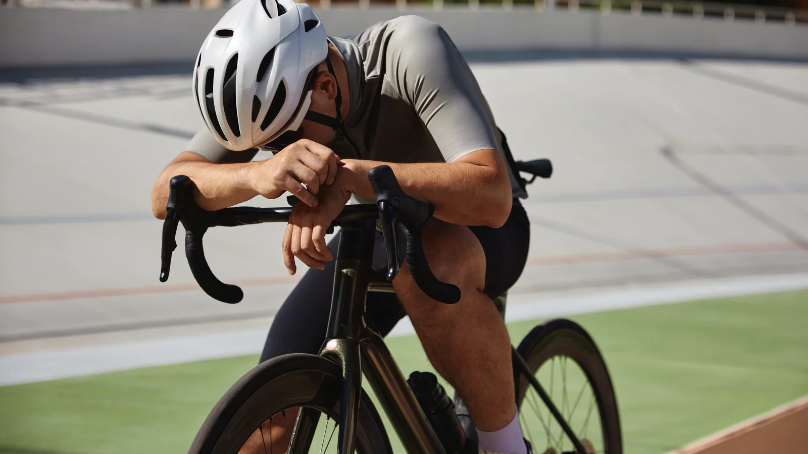Cycliste épuisé penché sur son guidon après un effort intense sur piste