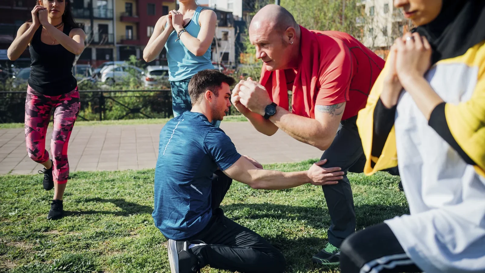 Coach corrigeant la posture d'un pratiquant lors d'un cours collectif en extérieur