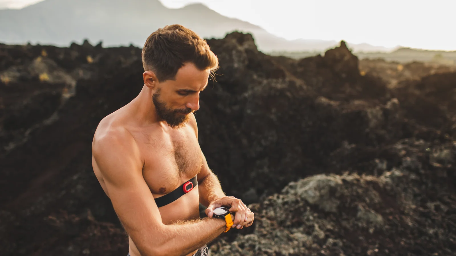 Coureur vérifiant sa montre cardio avec une ceinture pectorale, en pleine nature