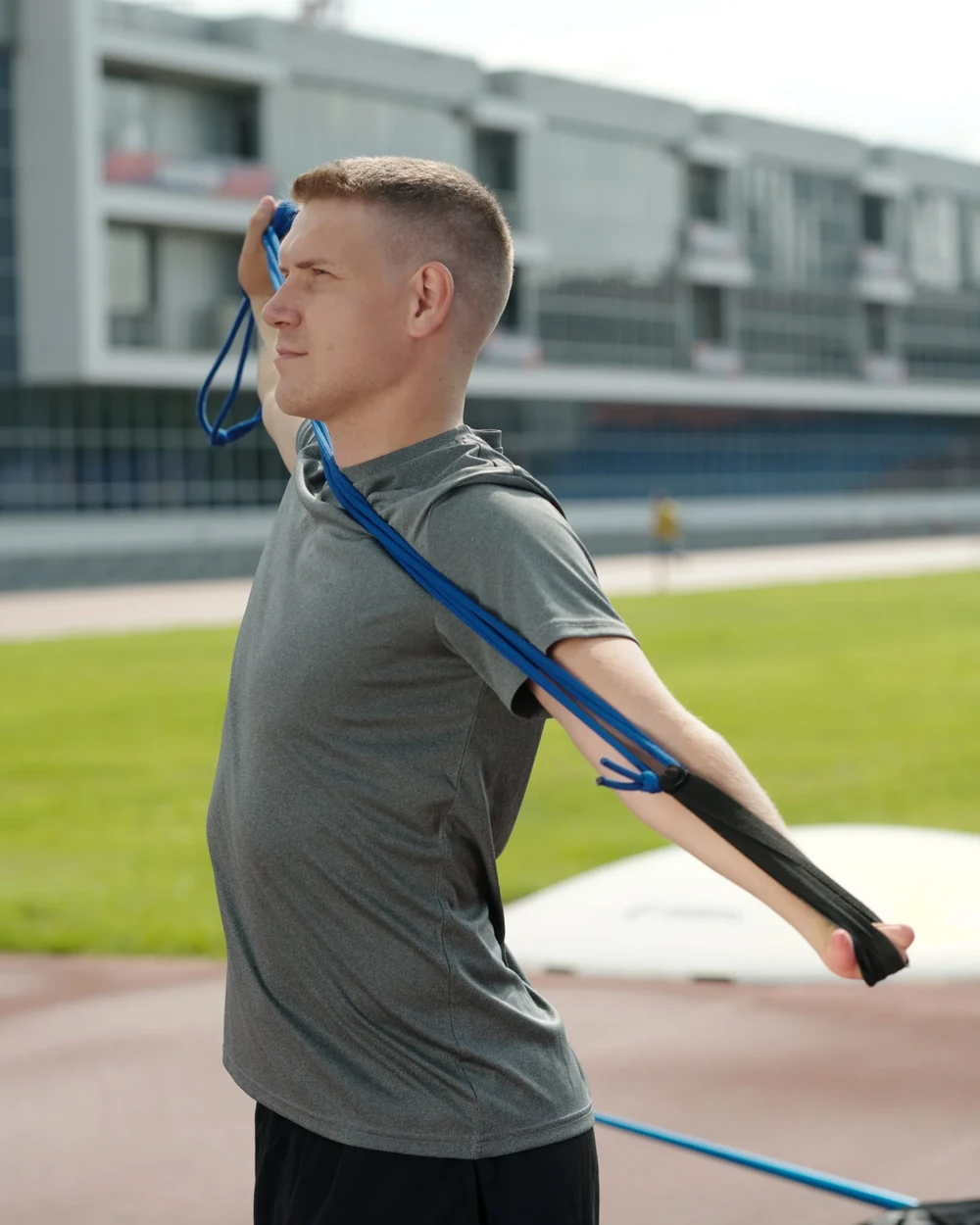 Sportif travaillant la mobilité de son épaule avec un élastique en extérieur
