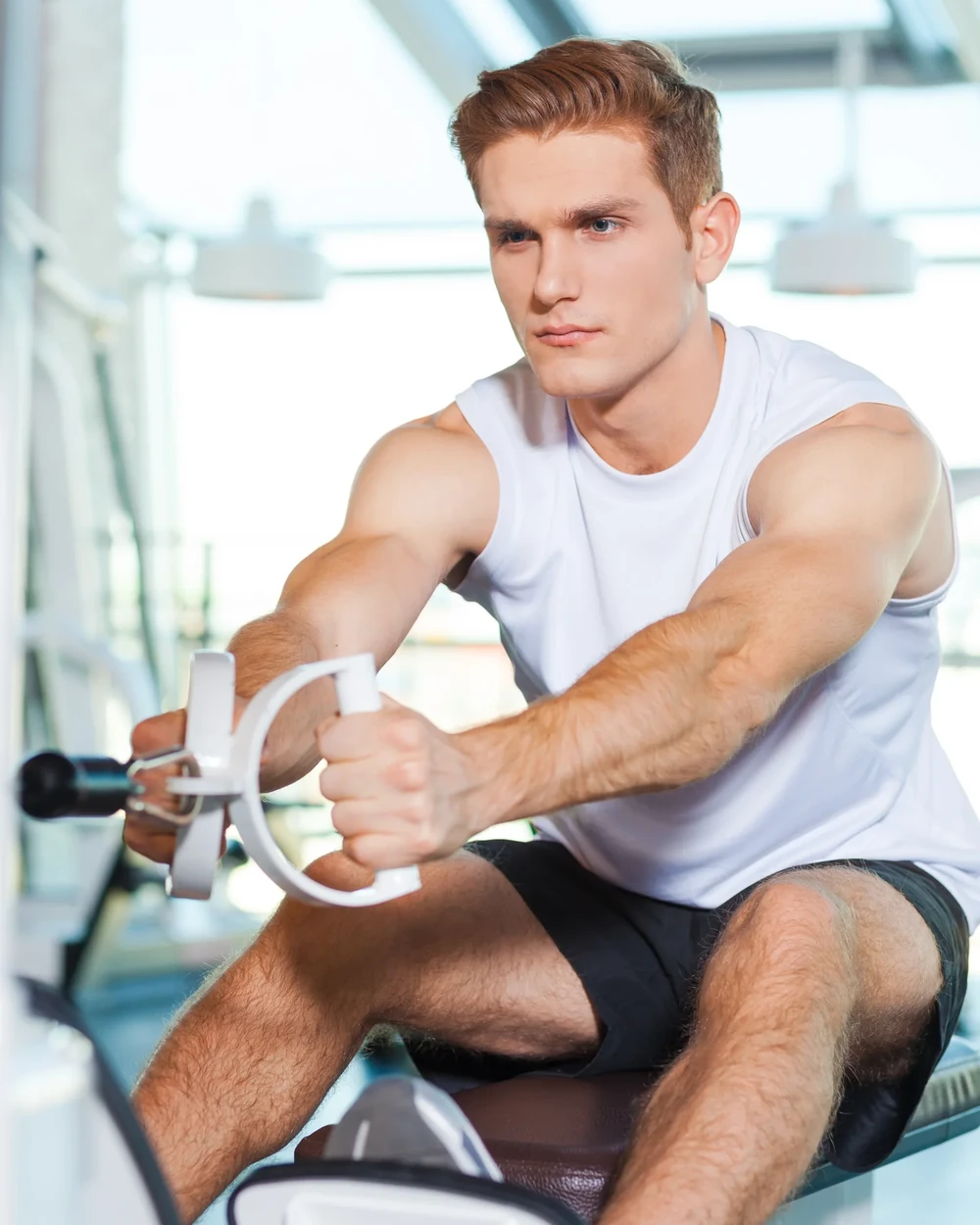 Sportif réalisant un exercice de renforcement des épaules sur machine en salle